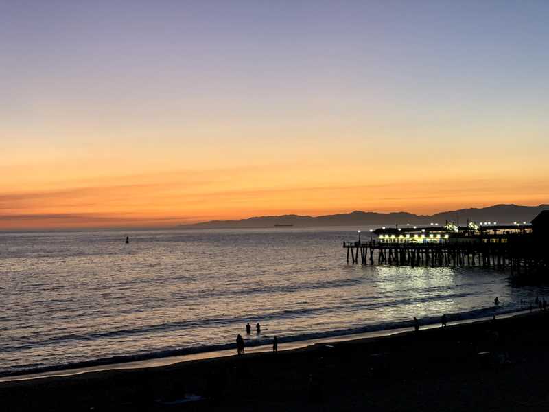 A sunset with the sun going behind the pacific ocean with the Redondo Beach pier in view