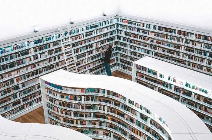 a long, curvy bookshelf with a man looking for a book